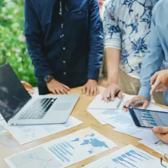 Team discute grafici e dati su un tavolo all'aperto, pianificando i loro buoni propositi per il futuro.