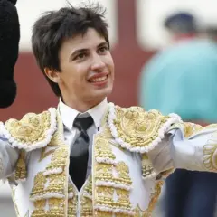 Francisco José Espada, torero, sonríe con su traje de luces dorado y blanco, alzando la montera y el capote.
