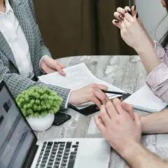 Rodzina omawia formalności związane z przepisaniem mieszkania na dziecko. Na stole dokumenty, laptop i notatnik.