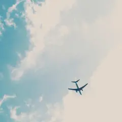 Un avion Volotea, peut-être en retard, traverse un ciel bleu parsemé de nuages cotonneux.