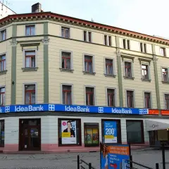 Elegancki budynek z szyldami Idea Bank i Cafe Qbek. W witrynach banku reklamy kredytów i usług.