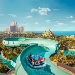 Familie hat Spaß im Dubai Wasserpark auf einer Rutsche, mit dem Atlantis Hotel im Hintergrund.