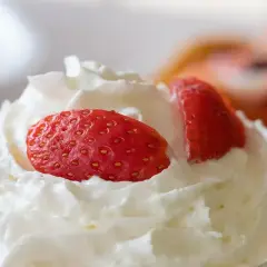 Chantilly aérienne garnie de fraises fraîches. Une invitation à découvrir comment faire de la chantilly maison pour un dessert parfait.