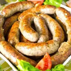 Pyszna biała kiełbasa surowa, idealna do pieczenia. Podana z sałatą i pomidorem.