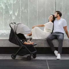 Szczęśliwi rodzice odpoczywają przy fontannie, podczas gdy ich 3 miesięczne dziecko śpi w spacerówce.