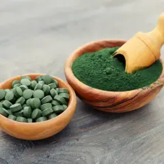 Chlorella i spirulina efekty: zielone tabletki i proszek w drewnianych miseczkach, gotowe do spożycia dla zdrowia.