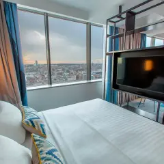 Pokój w hotelu Courtyard w Katowicach z widokiem na miasto. Łóżko, telewizor i zasłony.