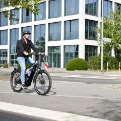 Mann fährt mit E-Bike durch eine moderne Stadt in Deutschland.