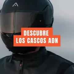 Motociclista con casco integral negro y chaqueta de cuero. El texto dice "DESCUBRE LOS CASCOS ADN". Un casco jet prohibido para esta aventura.