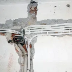 Widoczne przewody elektryczne w peszlach, częściowo ukryte w bruzdach w ścianie. Instalacja aluminiowa w trakcie prac.