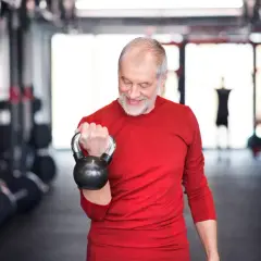Ein älterer Mann trainiert mit einer Kettlebell. Ein guter Trainingsplan für Krafttraining ab 60 Jahren hält ihn fit.