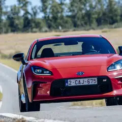 La Toyota sportiva rossa sfreccia su una strada tortuosa, con il sole che illumina il suo design aggressivo.