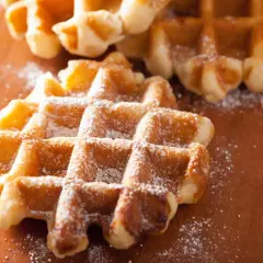 Gaufres liégeoises dorées saupoudrées de sucre glace sur une planche en bois. Un délice croustillant.
