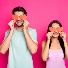 Coppia sorridente con cuori rossi sugli occhi, un modo giocoso per scoprire trucchi psicologici per capire se gli piaci.