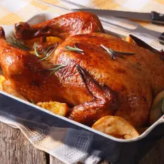 Un délicieux filet de poulet au barbecue, doré et juteux, servi avec des quartiers d'orange et des pommes de terre rôties.