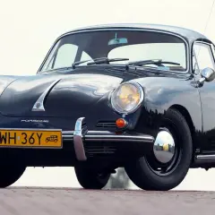 Czarne, zabytkowe auto Porsche z lat 50. XX wieku, z charakterystycznym przodem i żółtą tablicą rejestracyjną.