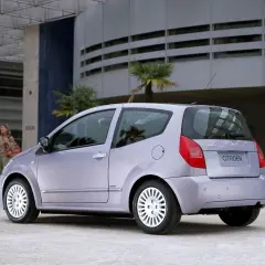 Jasnoszary Citroën C2 z parą na tle nowoczesnego budynku.