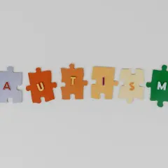 Kolorowe puzzle układają się w napis AUTISM. Każdy element symbolizuje inny stopień niepełnosprawności w spektrum autyzmu.