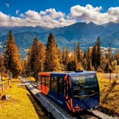 Kolejka linowa w Zakopanem pnie się wśród jesiennych drzew, oferując widok na Tatry.