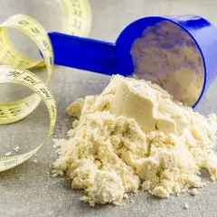 Miarka z proszkiem, być może kazeina, obok taśmy mierniczej. Idealne do budowania masy mięśniowej.