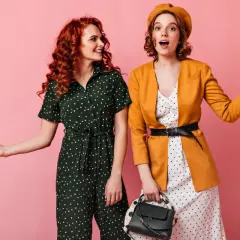 Dwie kobiety w strojach w groszki i stylu vintage na różowym tle.