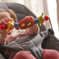 Maluch bawi się zabawką w leżaczku BabyBjorn. Od kiedy dziecko zaczyna sięgać po przedmioty, taki leżaczek jest idealny.