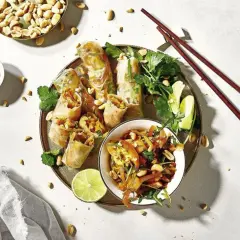 Frühlingsrollen mit Erdnüssen, Limette und Koriander – ein typisch asiatisches Essen, serviert mit Sojasauce und Stäbchen.