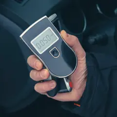 Dłoń trzyma alkomat z wyświetlaczem pokazującym 0.050.