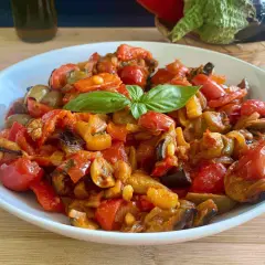 Caponata ricetta semplice: melanzane, peperoni e pomodorini cotti insieme, guarnita con basilico fresco. Un contorno saporito e colorato.