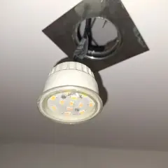Oprawa natynkowa GU10 z widoczną żarówką LED, zamontowana na suficie.