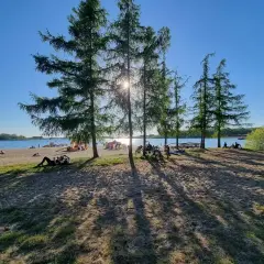 Słoneczny dzień nad jeziorem, ludzie odpoczywają na plaży, rowery czekają. Skorzęcin atrakcje to idealne miejsce na relaks.