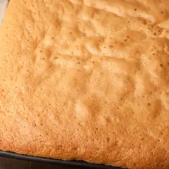 Puszysty, złocisty biszkopt w formie, gotowy do pieczenia. Idealny na tort lub jako samodzielny deser.