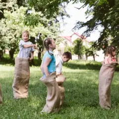 Barn hoppar säcklopp i trädgården. Perfekta fest idéer för en rolig sommardag!