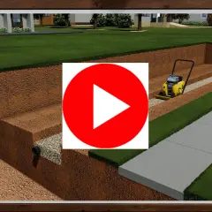 Construcción de un muro de contención con compactadora. Se ve la excavación, drenaje y preparación del terreno para un jardín y acera.