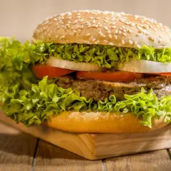 Soczysty burger z wołowiny, sałatą, pomidorem i cebulą w bułce do hamburgerów z sezamem. Idealny pomysł, co zrobić z bułki do hamburgerów.