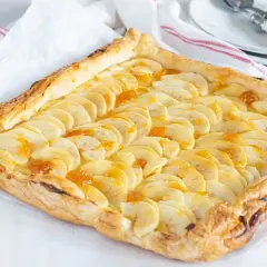Tarta de manzana con crema pastelera, con finas láminas de manzana y un glaseado dorado sobre hojaldre crujiente.