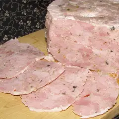 Schab z szynkowara bez peklowania, pokrojony w plastry, z widocznymi kawałkami mięsa i przypraw.
