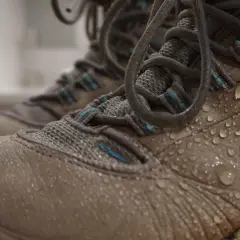 Close-up of tan hiking boots covered in water droplets, showing how to waterproof hiking boots effectively.