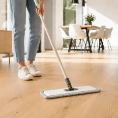 Pulire il parquet con rimedi della nonna, un gesto antico per una casa splendente. La persona pulisce il pavimento in legno con uno straccio.