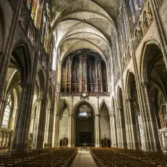 Wnętrze katedry Saint-Denis z organami i witrażami. Puste ławki czekają na wiernych w tej zabytkowej budowli.