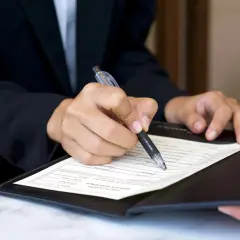 Dłoń w garniturze podpisuje dokument. Czy to umowa, czy może zgoda na warunki, które nawet siła wyższa, jak kodeks pracy, musi uszanować?
