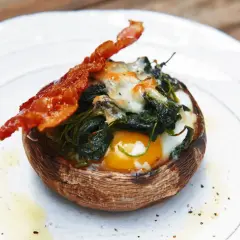 Gefüllter Portobello Pilz mit Ei, Spinat und Käse, garniert mit knusprigem Speck. Ein einfaches und leckeres Portobello Pilz Rezept.