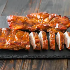 Soczyste, glazurowane żeberka wieprzowe, pokrojone na kawałki. Idealne do grillowania, zastanawiasz się, jak długo wędzić polędwiczki wieprzowe, by osiągnąć taki efekt?