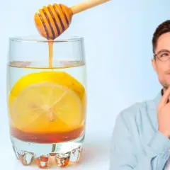 Hombre pensativo junto a un vaso de agua con limón y miel, perfecto para empezar el día.