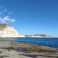 Costa rocosa y mar azul en la cala cortada Almería. El sol ilumina las formaciones rocosas y el agua cristalina.