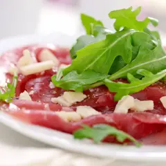 Cienkie plastry wołowiny z rukolą i parmezanem, skropione pysznym sosem do carpaccio.