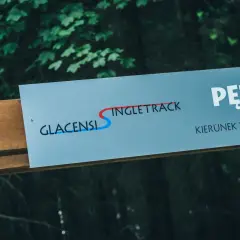 Tablica informacyjna z napisem "GLACENSIS SINGLETRACK" i strzałką wskazującą kierunek.