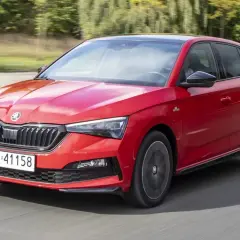Czerwona Skoda Scala Monte Carlo pędzi po drodze, błyszcząc w słońcu.