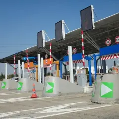 Voies de péage avec des indicateurs verts et orange. Une voie semble réservée au péage gratuit pour les handicapés.