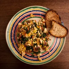 Revuelto de tofu con maíz y espinacas, servido con pan tostado en un plato colorido.